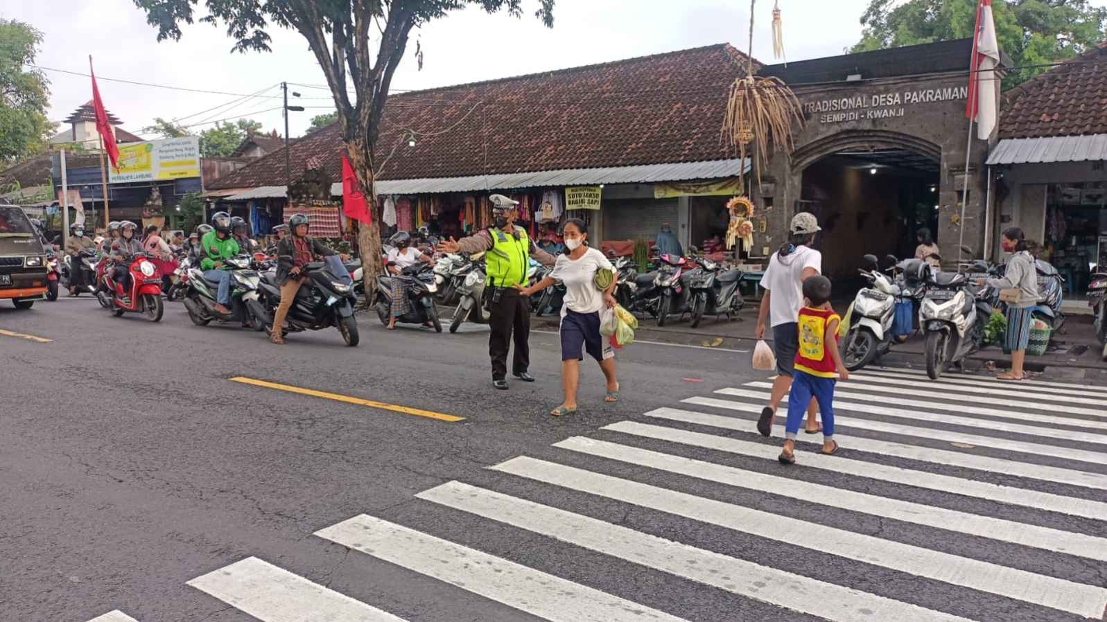 Polisi Lalulintas Membantu Masyarakat Menyebrang Jalan